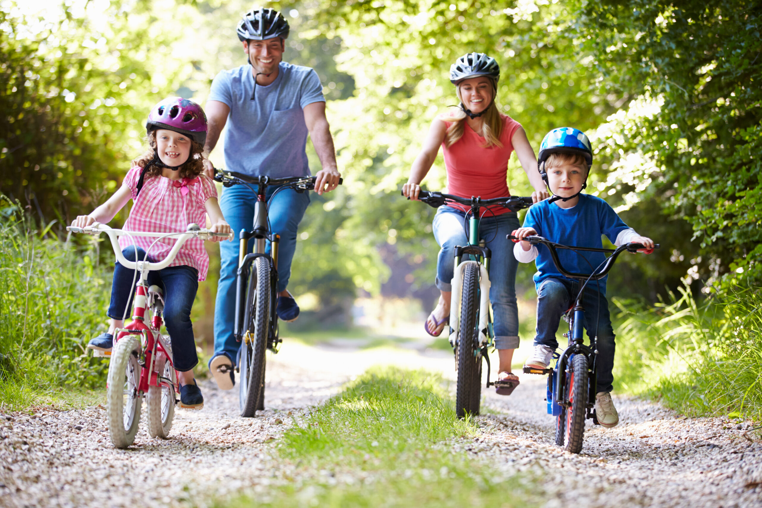 Zwei Eltern und zwei Kinder fahren Fahrrad auf einem Waldweg